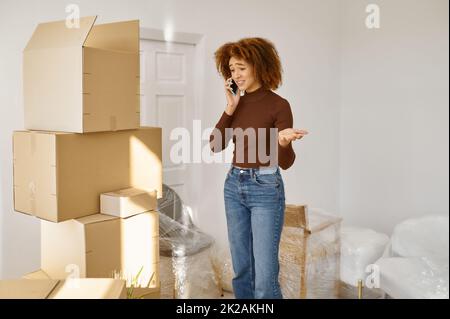 Giovane donna che parla di telefono tra scatole di cartone Foto Stock