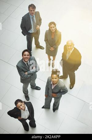 Weve ha ottenuto i nostri obiettivi fissati sul successo. Ritratto ad alto angolo di un gruppo di uomini d'affari che si trova nella lobby dell'ufficio. Foto Stock