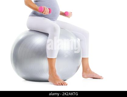 Mantenere la sua forma fisica. Immagine ritagliata di una donna che si sta allenando con una palla da ginnastica e pesi leggeri. Foto Stock