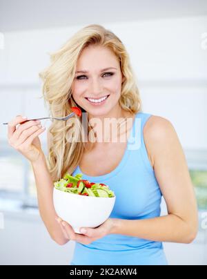 Il giusto tipo di dieta. Ritratto di una bellissima giovane donna che mangia un'insalata sana. Foto Stock