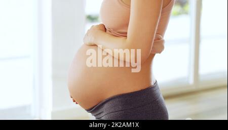 Im innamorato di un bambino che ho incontrato ancora. Colpo di una donna incinta che tiene il suo ventre a casa. Foto Stock