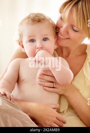 Ceneri orgogliosi del suo ragazzino. Carino bambino ragazzo che ti guarda mentre è tenuto da sua madre sorridente. Foto Stock