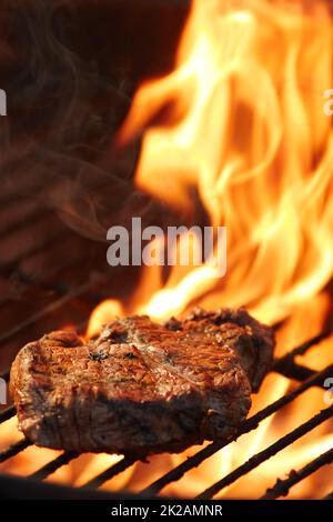 Il gusto fumoso dell'estate. Primo piano di una gustosa bistecca di cottura sul fuoco. Foto Stock