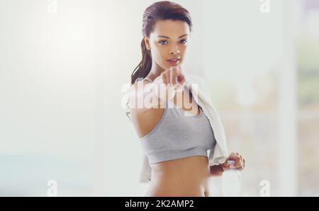 Inizia oggi stesso. Ritratto ritagliato di una giovane donna attraente che punta verso la fotocamera durante il suo allenamento a casa. Foto Stock