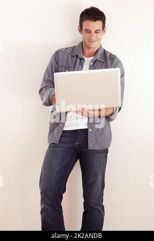 Accesso a Internet da qualsiasi luogo. Un bel giovane uomo che lavora sul suo laptop. Foto Stock