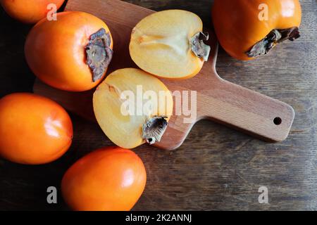 Frutta fresca biologica matura Persimmons con fetta su vecchio sfondo tavolo di legno. Vista dall'alto. Disposizione piatta. Spazio di copia per testo e contenuto Foto Stock