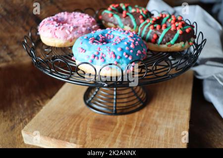 Ciambella con glassa blu, cioccolato e vaniglia su sfondo di legno scuro Foto Stock