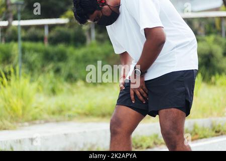 sport runner uomo nero indossare orologio mani giunto di tenuta gamba ha dolore alle cosce mentre corre Foto Stock