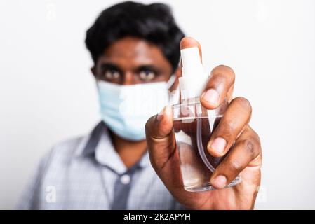 uomo nero che indossa maschera protettiva paura di tenere gli occhi mostrare lo spray igienizzante Foto Stock