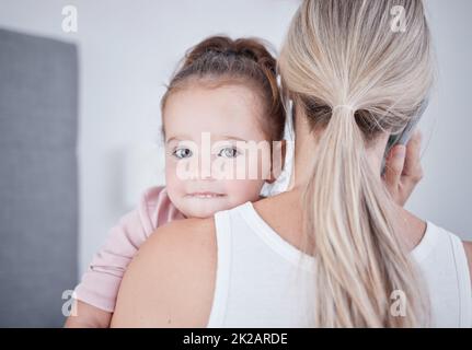 Il bambino, la comunicazione e la mamma parlano durante una conversazione telefonica mentre il multitasking durante una chiamata di lavoro. Lavoro da casa madre singola che tiene una bambina Foto Stock