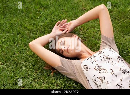 L'erba è più verde sul lato che permette di sdraiarsi. Una bella giovane donna sdraiata sull'erba. Foto Stock