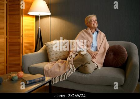 Donna anziana soddisfatta avvolta in coperta rilassante Foto Stock