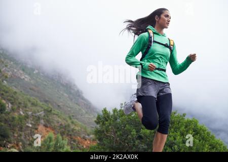 Progredisce nella sua idoneità giornaliere. Una giovane donna che si snoda lungo una strada di montagna in una mattinata frizzante. Foto Stock