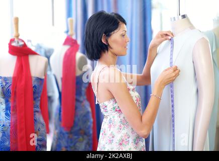Shes un sarto esperto. Una giovane etnia attraente che prende le misure del vestito. Foto Stock