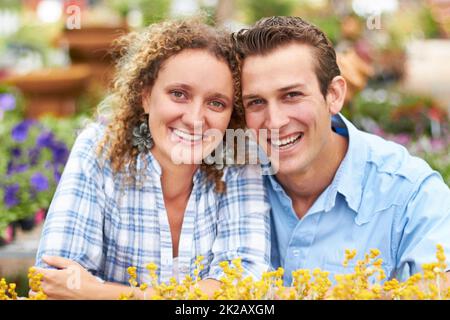 Amiamo il giardinaggio. Una coppia felice che sceglie i fiori in un vivaio. Foto Stock