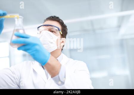 Vediamo cosa succede. Shot ad angolo basso di un chimico che mescola prodotti chimici. Foto Stock