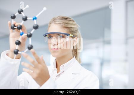 Sull'orlo di un break-through medico. Un giovane scienziato stupendo che guarda un modello di struttura molecolare. Foto Stock