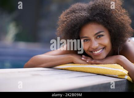 Potrei stare qui tutto il giorno. Bella donna etnica sdraiata presso la piscina. Foto Stock