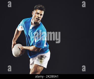 È ora di provare. Studio girato di un giocatore di rugby che passa la palla su uno sfondo nero. Foto Stock