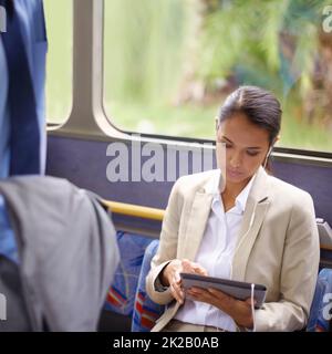 Non si annoiava mai sull'autobus. Scatto di una donna d'affari che utilizza un tablet digitale mentre si viaggia su un autobus. Foto Stock