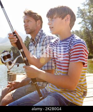 Guardate che la linea va. Fucilato di un padre e di un figlio che pescano insieme. Foto Stock