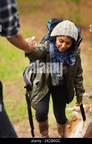 Prestare una mano d'aiuto. Giovane donna che riceve una mano di aiuto dal suo ragazzo mentre fuori escursioni. Foto Stock