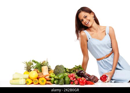 Fare scelte sane e sentirsi grandi. Giovane donna sorridente con un assortimento di verdure sane e fresche. Foto Stock