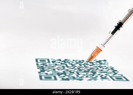 Un primo piano con codice QR e una siringa medica Foto Stock