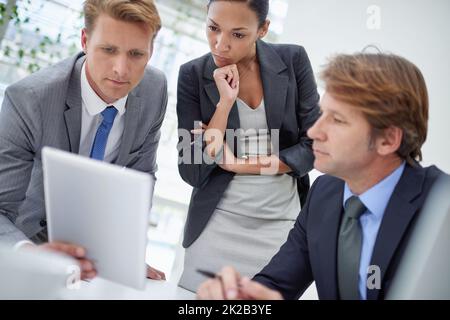 Theyve ha ottenuto alcune decisioni importanti da prendere. Un giovane uomo d'affari che mostra ai suoi colleghi qualcosa su un tablet digitale. Foto Stock