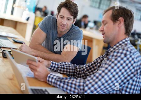 Questo è un aspetto che devi vedere. Colleghi che parlano insieme su un tablet digitale alla scrivania in un grande ufficio. Foto Stock