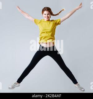 Stella salta. Studio a tutta lunghezza girato di una bella giovane donna che fa un salto stella. Foto Stock