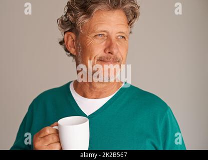 Assapori qualcosa di caldo in un freddo pomeriggio. Ripresa da studio ritagliata di un bell'uomo maturo in possesso di una tazza. Foto Stock