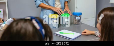 Insegnante e studenti in un'aula di ecologia imparando a riciclare con la cernita dei rifiuti Foto Stock