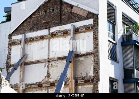 Supporto di un muro di costruzione con puntoni in legno dopo la demolizione di un vecchio edificio Foto Stock