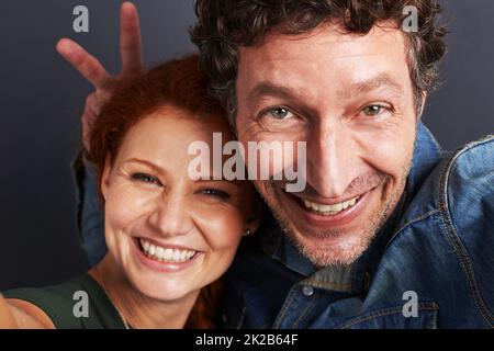 Deve amare il divertimento. Ritratto di una giovane coppia felice che fa una posa divertente per un selfie. Foto Stock