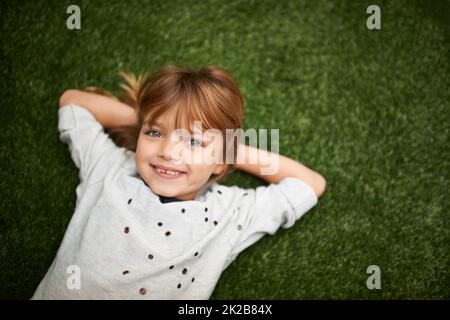 Ceneri un incantatore. Bambina sdraiata sull'erba con le mani dietro la testa. Foto Stock