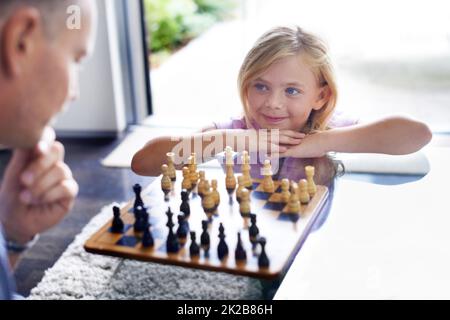 Insegnandole l'abilità della strategia. Un padre che gioca a scacchi con la figlia. Foto Stock