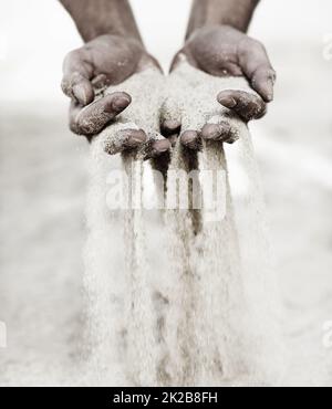 Toccare la spiaggia. Colpo di un uomo con una manciata di sabbia che cade attraverso le sue dita. Foto Stock