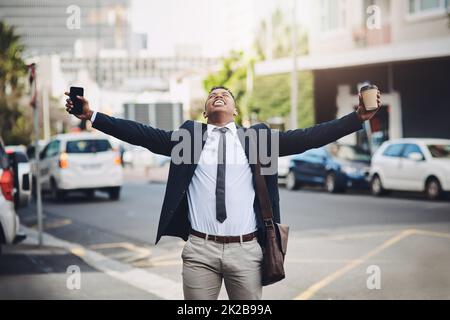 Il duro lavoro paga sempre alla fine. Colpo di un giovane uomo d'affari felice in piedi con le sue braccia distese in città. Foto Stock