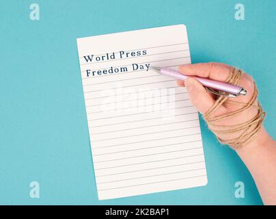 La Giornata Mondiale della libertà di stampa è in piedi su un documento, la mano con la penna è incatenata, la libertà di parola, annullare la cultura, la scrittura giornalista Foto Stock