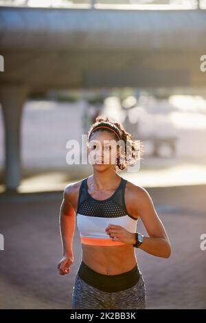 Esecuzione con determinazione. Scatto corto di una giovane donna attraente che prende una corsa attraverso la città. Foto Stock