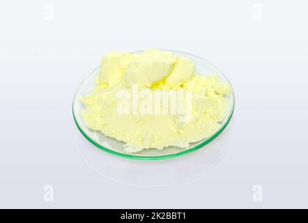 Polvere di zolfo in vetro da orologio chimico. Primo piano ingrediente chimico su tavola bianca da laboratorio. Foto Stock