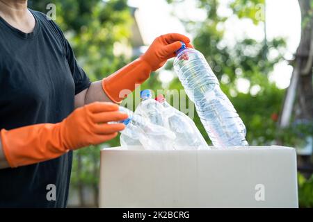 Donna asiatica volontario trasportare bottiglie di plastica di acqua in spazzatura scatola rifiuti in parco, riciclare ambiente ecologia concetto. Foto Stock