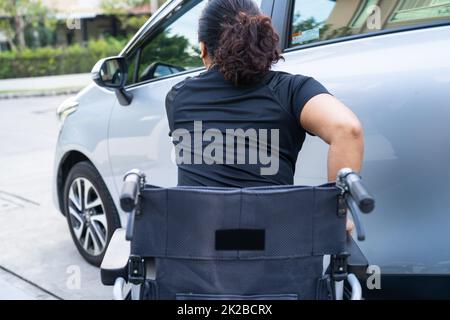 Donna di disabilità asiatica su sedia a rotelle che si trova nella sua auto. Concetto di accessibilità. Foto Stock