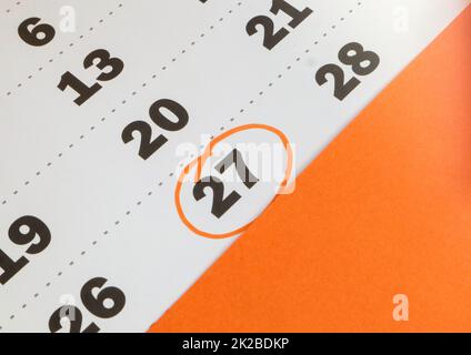Primo piano promemoria della data memorabile registrata nel calendario del 27th, calendario su sfondo arancione Foto Stock