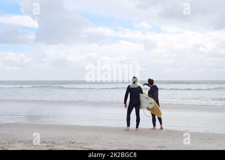 Surf con il mio migliore compagno. Due giovani surfisti sulla spiaggia. Foto Stock