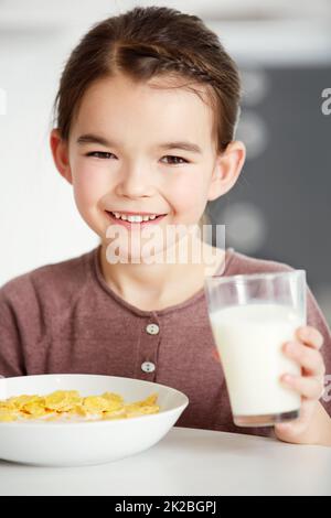 Colazione completa. Ritratto di una ragazza carina che beve un bicchiere di latte con il suo cereale. Foto Stock