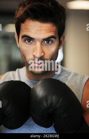 HES pronto ad affrontare qualsiasi concorrente. Ritratto di un uomo concentrato che indossa guanti da boxe e abbigliamento sportivo in posa pronto a combattere. Foto Stock