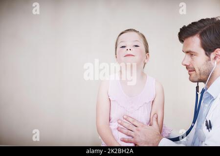 Respira profondamente Un giovane medico di sesso maschile che effettua una visita medica su una bambina. Foto Stock