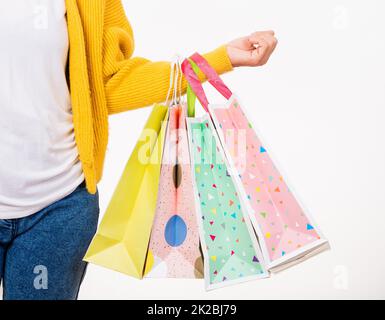 donna mano indossa una camicia gialla che tiene borse di shopping multicolore Foto Stock